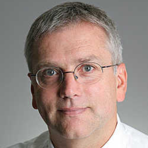 Porträt eines Mannes mit Brille und grauen Haaren, der in die Kamera schaut.