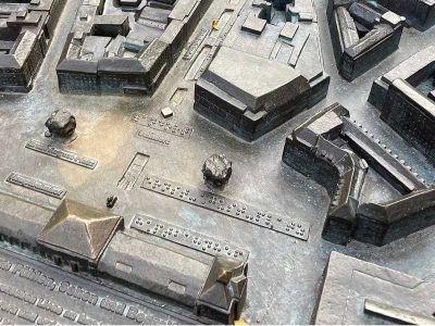 Detailansicht eines Stadtmodells mit verschiedenen Gebäuden und Straßen in Bronze.