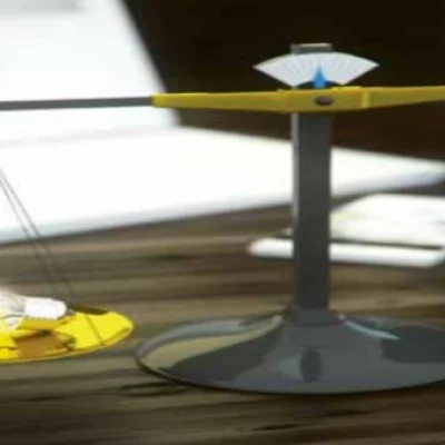 Waage mit einer Glühbirne auf der linken Seite und einer Wasserflasche auf der rechten Seite.