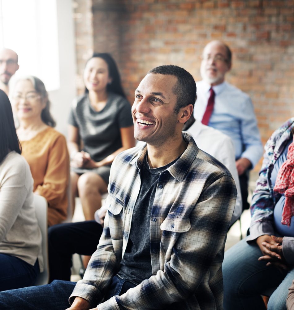 Eine Gruppe von Menschen, die lächeln und an einer Veranstaltung teilnehmen, mit verschiedenen Gesichtsausdrücken.